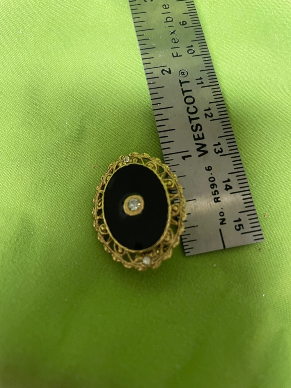 Broach black Onyx stone in the center two diamonds on the side.